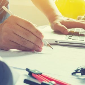 Image of a contractor working on a laptop holding a pencil