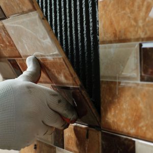 Man placing tiles on wall